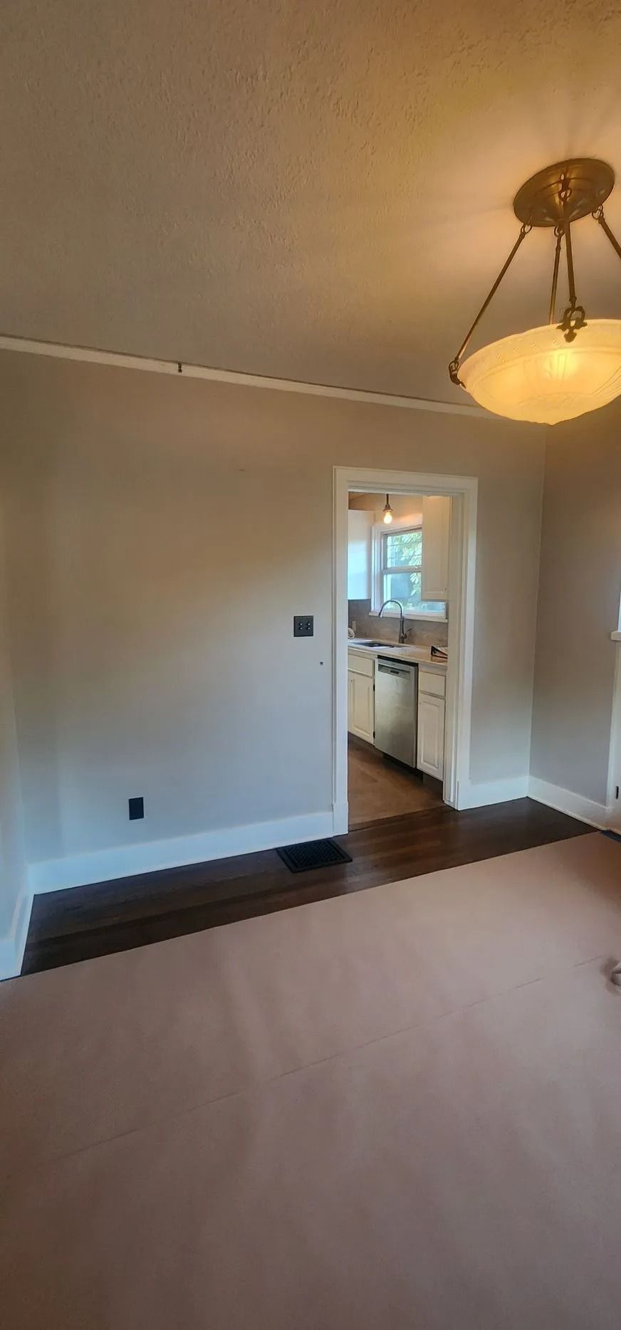 Unfurnished room leading to bright kitchen