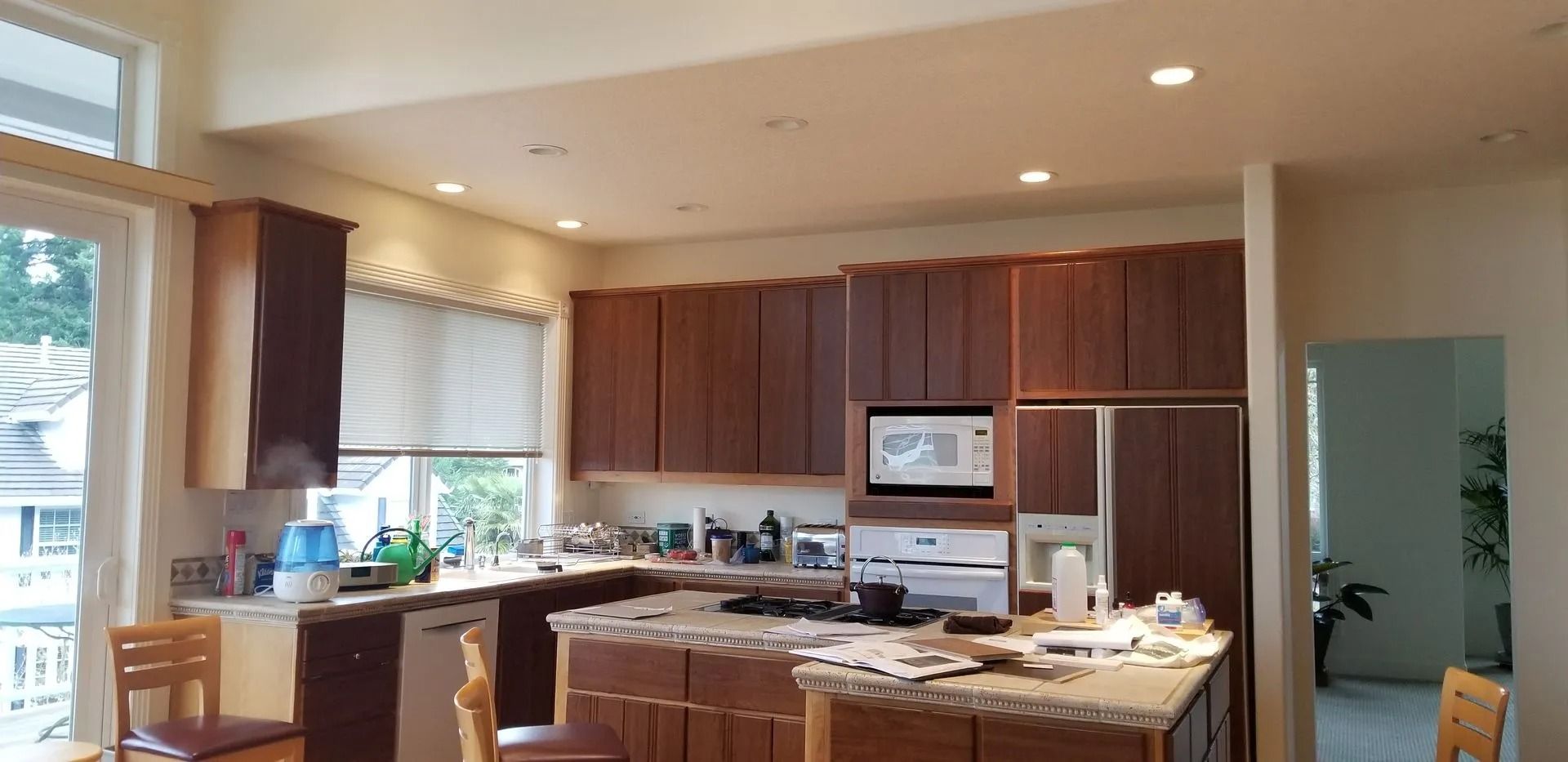 Sunlit kitchen with appliances and chairs