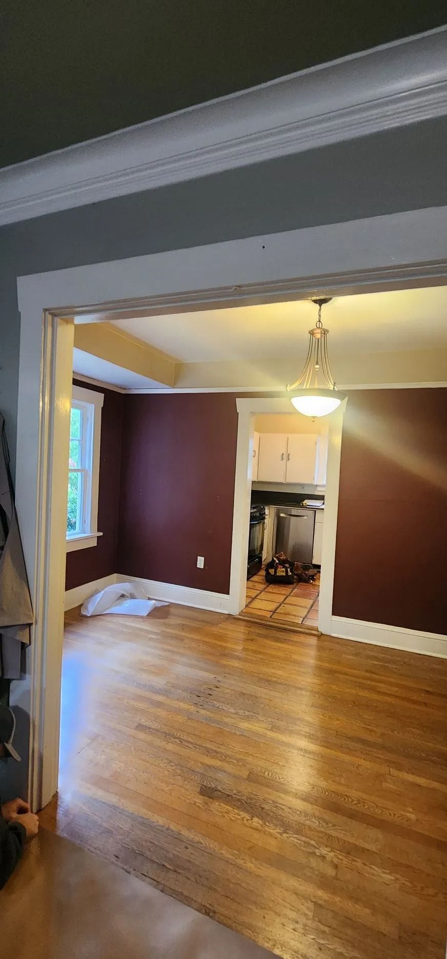 Empty room with hardwood floor and chandelier.