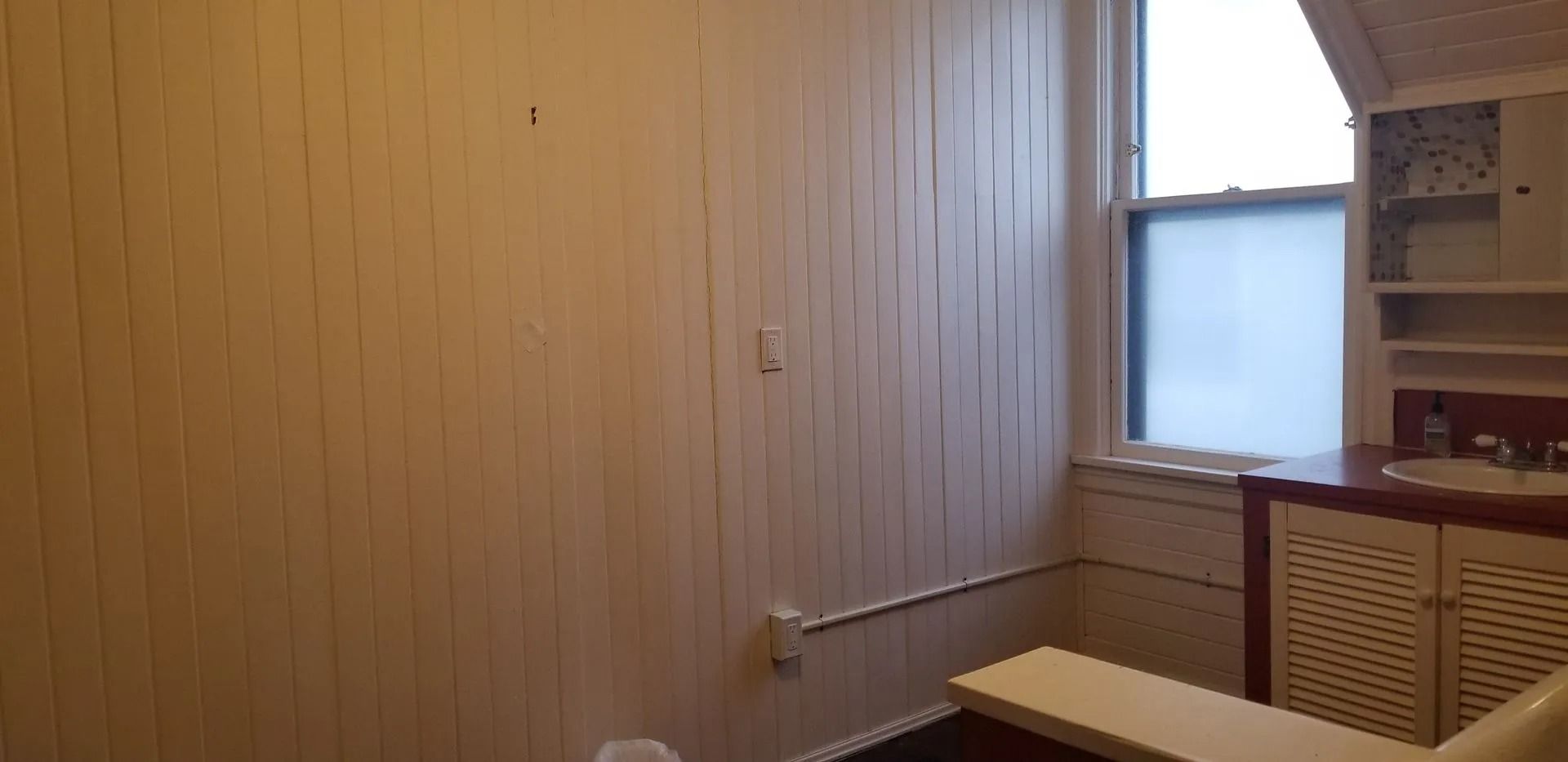 Wood-paneled bathroom with frosted window