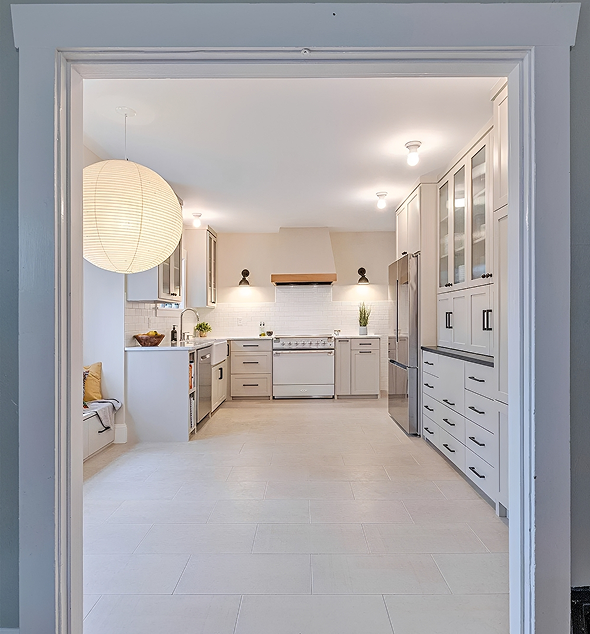 Modern kitchen with white cabinets and lighting.