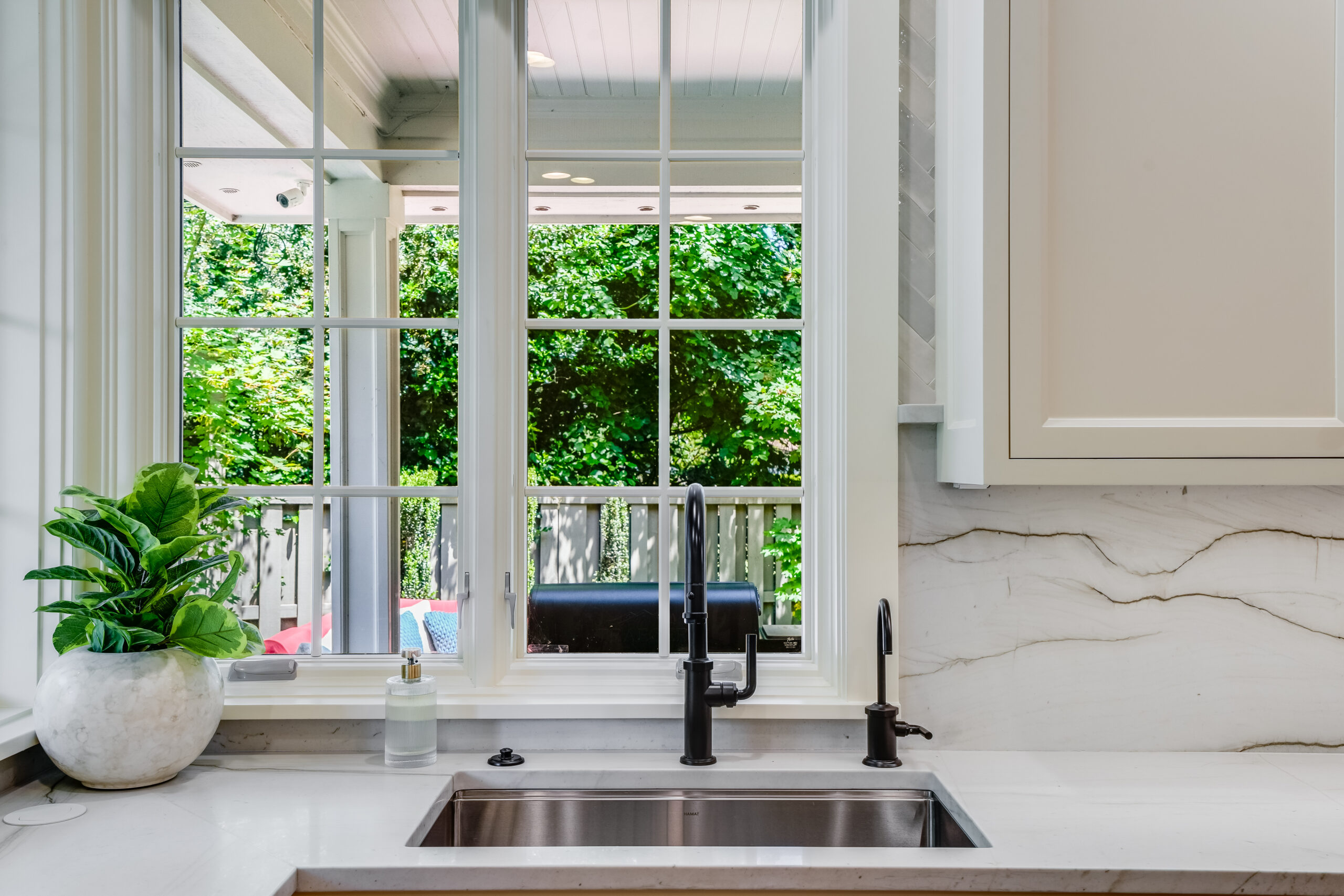 Kitchen sink with window overlooking leafy backyard