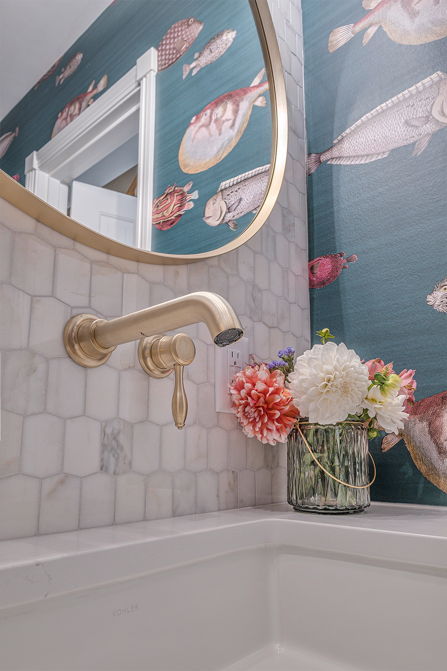 Bathroom sink with brass faucet and fish wallpaper