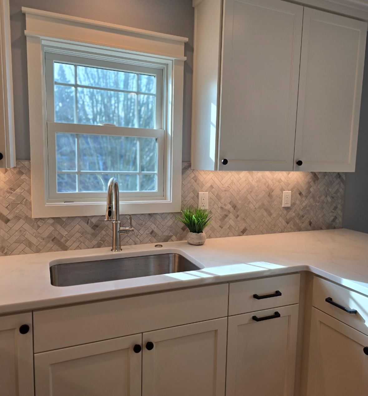 White kitchen sink with herringbone marble backsplash