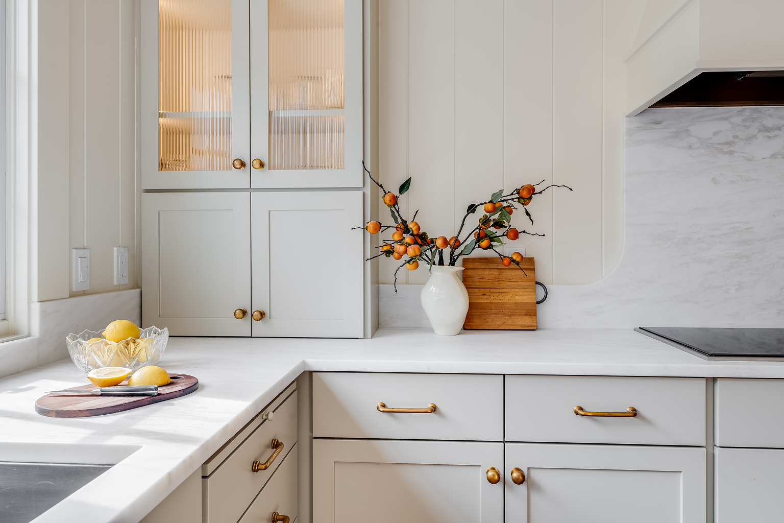 White kitchen countertop with vase of orange flowers